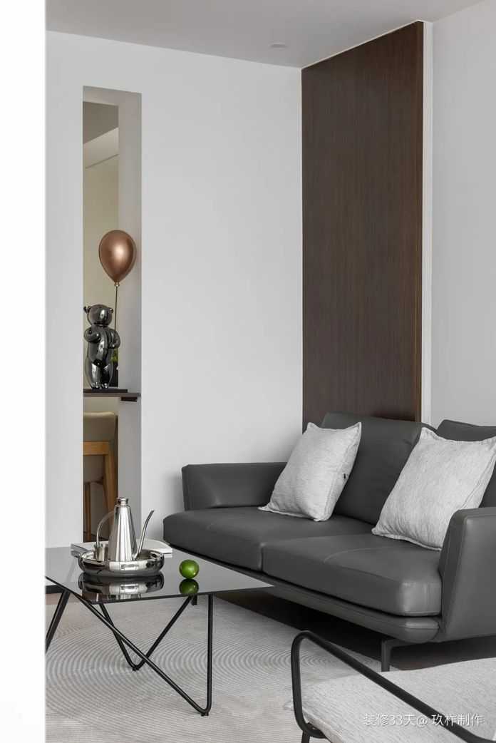 留白與木皮裝飾的沙發背景牆搭配深色皮質沙發，配合整體簡約的基調，給整個家增添幾分穩重