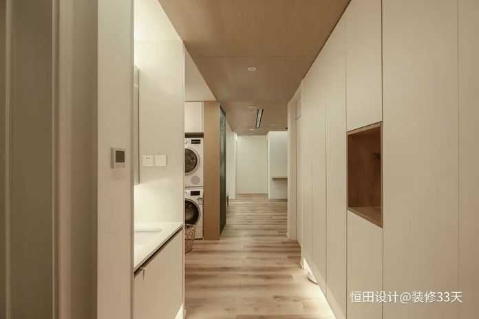 走道設計大面積定製櫃，中部留空輔以木色做置物區，將客衛洗手檯外接，提供更為便利的生活動線