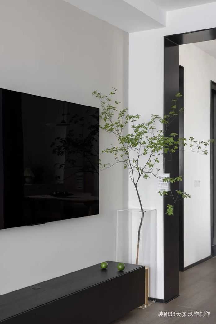 電視背景牆，無過多裝飾，僅僅是一面未經修飾的白牆，低調簡約，在黑色懸空式的電視櫃旁，還擠出了空間放置