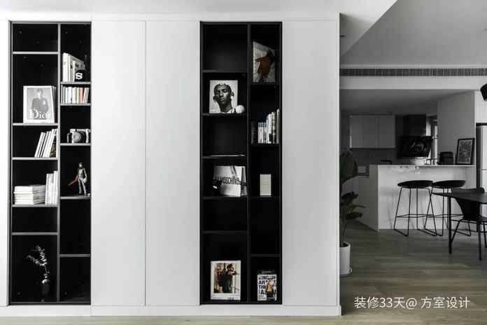 牆面櫃體採用黑與白的對比色，開放格擺放書籍和CD，隱藏的櫃門內增加收納空間